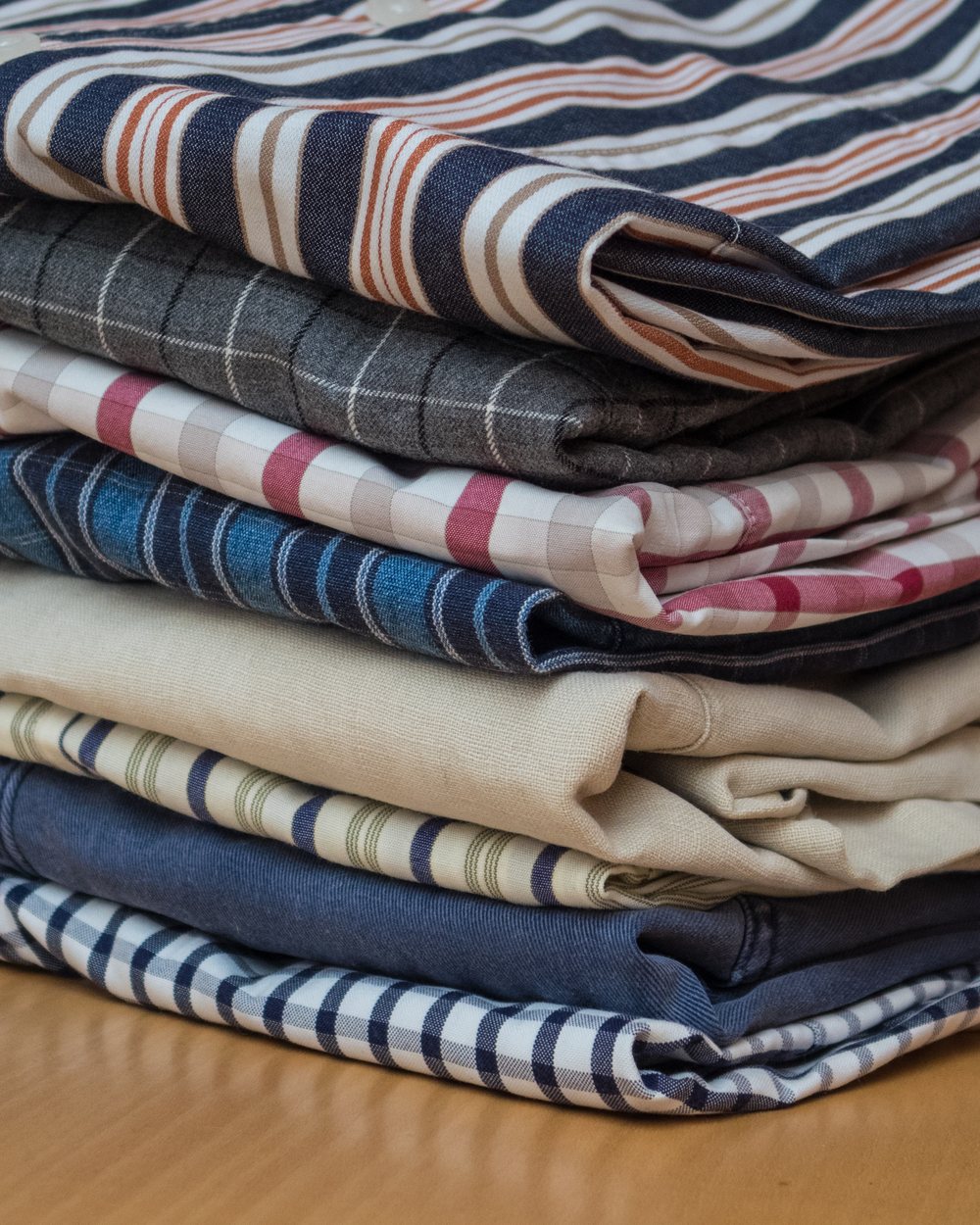 Stack of folded cotton shirts in stripes, checks and chambray