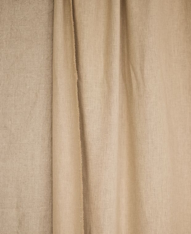 Beige cotton curtain fabric hanging in soft vertical folds