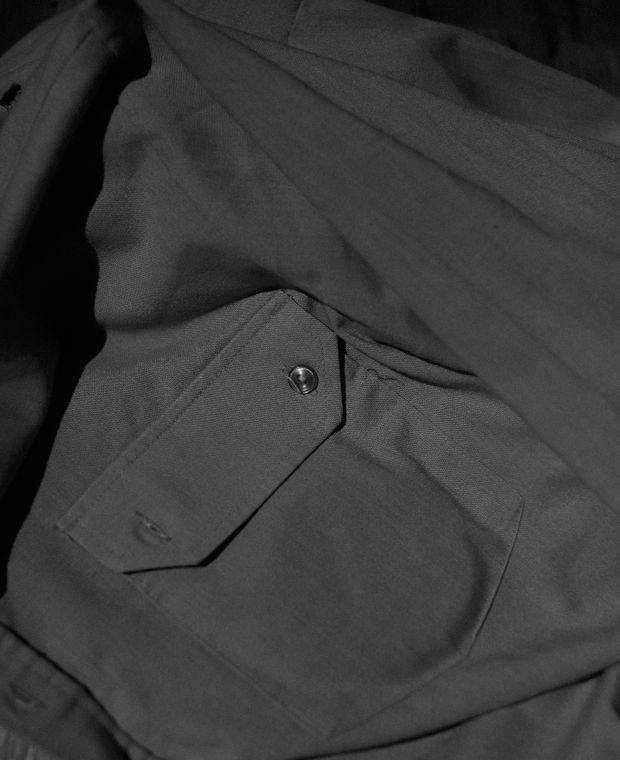 Close-up of grey trousers with a buttoned flap pocket