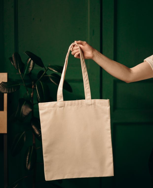 Plain cotton canvas tote bag held by its handles
