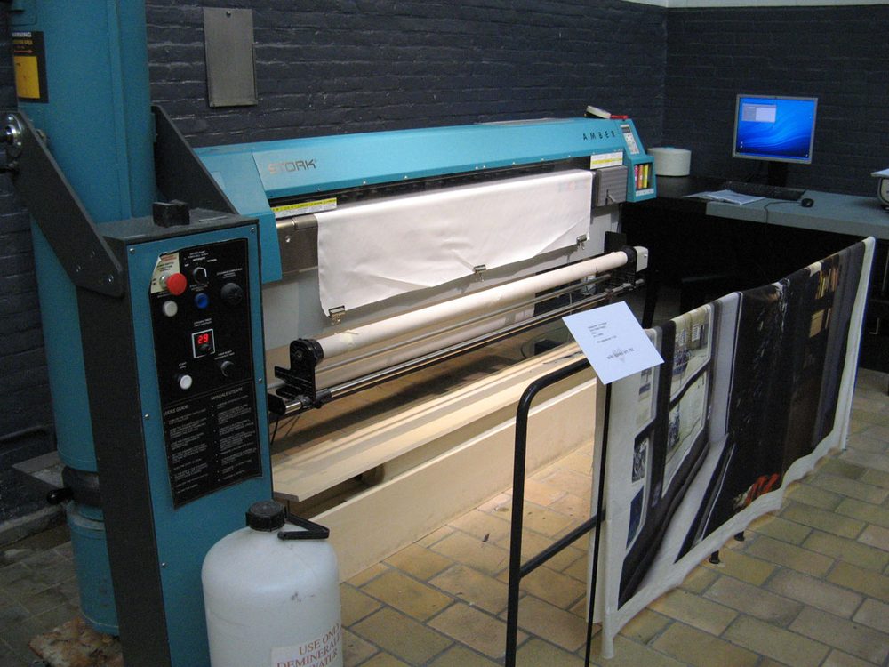 Wide-format digital textile printer with white fabric loaded on its feed roller