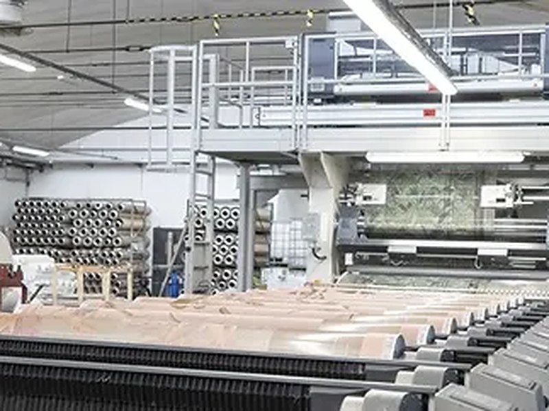 Rotary printing line, printed cloth running out under the gantry with the screen cylinders racked behind it