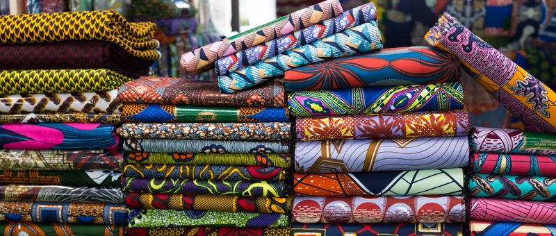 Stacks of folded cotton fabrics printed with bold, colourful repeating patterns
