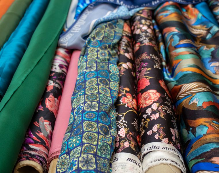 Rolls of printed fabric in florals, tile patterns and solid colours laid side by side