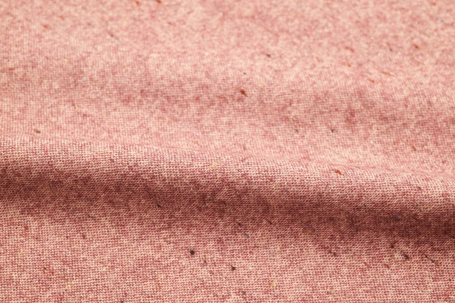 Close-up of soft rose-pink cotton fabric with small flecks of colour in the weave