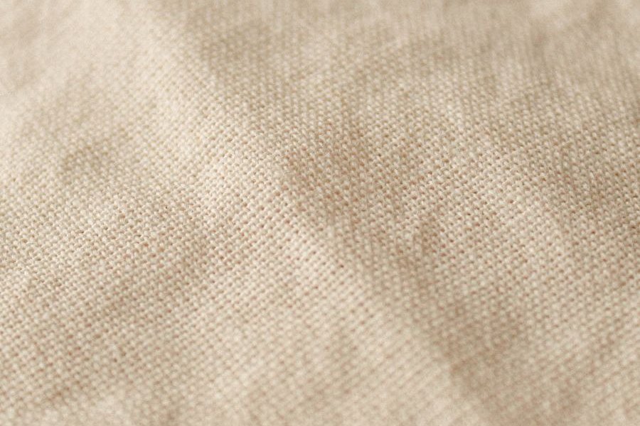 Close-up of a beige woven cotton showing the individual warp and weft threads